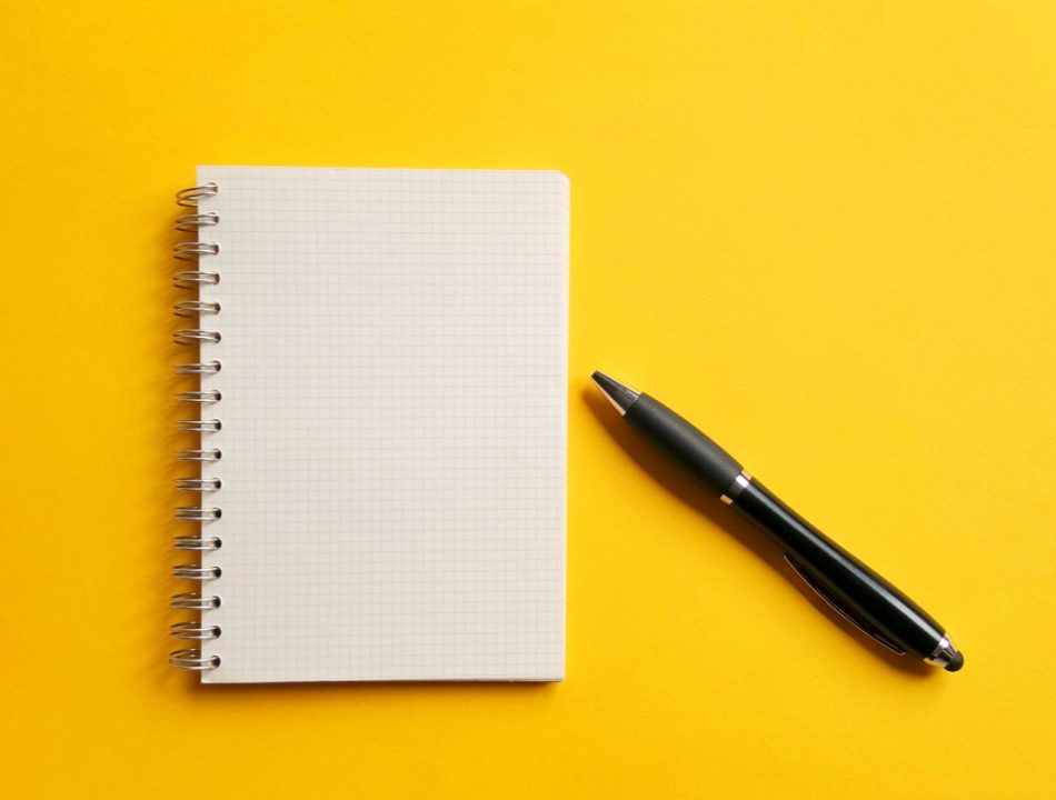 Notebook and pen on yellow backround, writing concept.